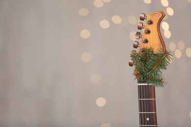 Guitar with fir tree twig against blurred lights, space for text. Christmas music