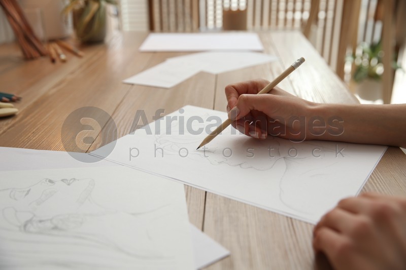 Young woman drawing male portrait at table indoors, closeup