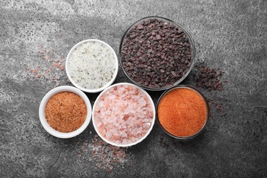Different kinds of salt on grey table, flat lay