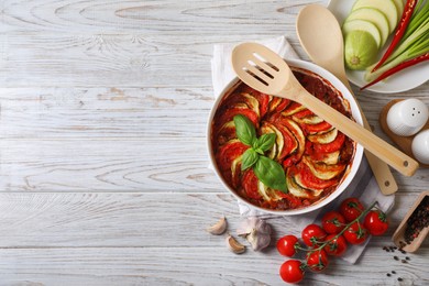 Photo of Delicious ratatouille and ingredients on white wooden table, flat lay. Space for text