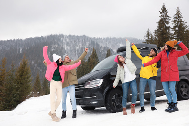 Happy people jumping near car on snowy road. Winter vacation