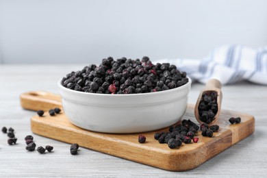 Bowl and scoop with dried blueberries on white wooden table