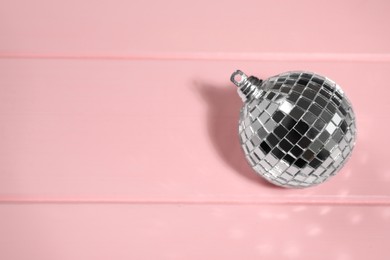 Shiny disco ball on pink wooden background, above view. Space for text