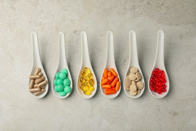 Spoons with different dietary supplements on light grey table, flat lay
