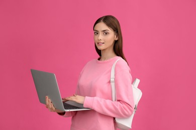 Teenage student with laptop and backpack on pink background