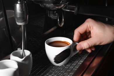 Photo of Barista making fresh aromatic espresso using professional coffee machine in cafe, closeup