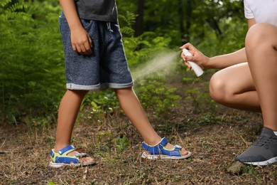 Woman applying insect repellent on her son's leg in park, closeup. Tick bites prevention