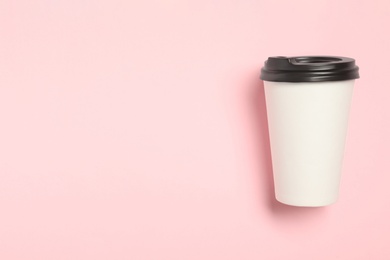 Takeaway paper coffee cup on pink background, top view. Space for text