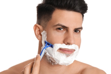Handsome man shaving with razor on white background, closeup