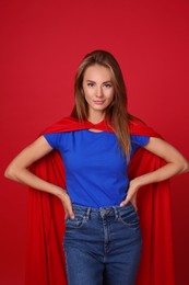 Confident woman wearing superhero cape on red background