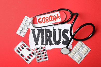 Flat lay composition with phrase CORONA VIRUS and medicines on red background