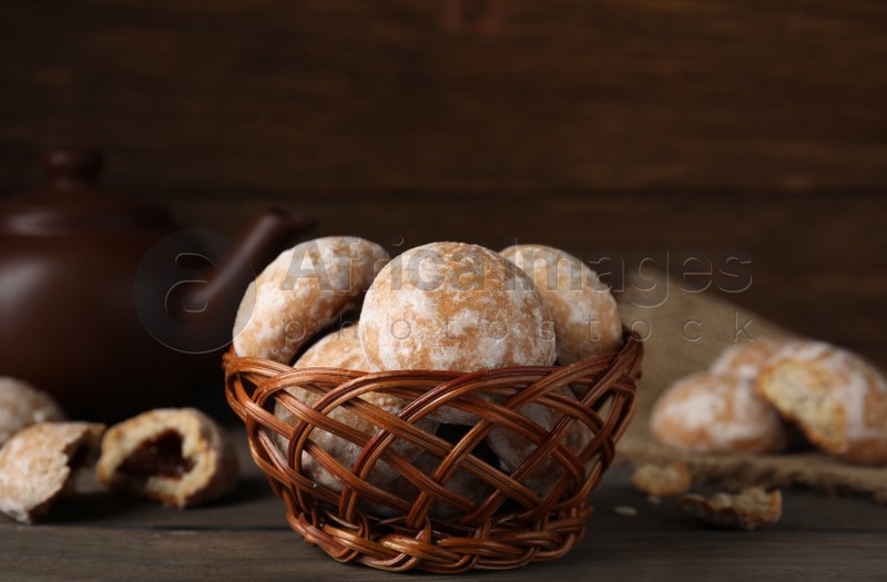 Photo of Tasty homemade gingerbread cookies in wicker basket on wooden table