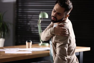 Photo of Man suffering from shoulder pain in office. Bad posture problem