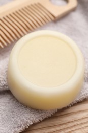 Solid shampoo bar and towel on wooden table, closeup