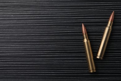 Two bullets on black wooden table, flat lay. Space for text