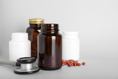 Bottles with pills and stethoscope on light background, space for text. Anemia treatment