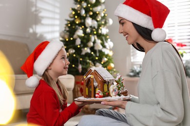 Photo of Mother and daughter with gingerbread house indoors