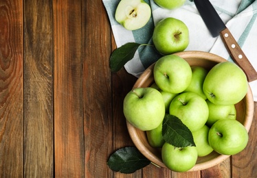Fresh ripe green apples and knife on wooden table, flat lay. Space for text