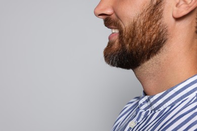 Profile portrait of smiling bearded man on grey background, closeup. Space for text