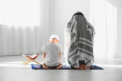 Muslim man and his son praying together indoors