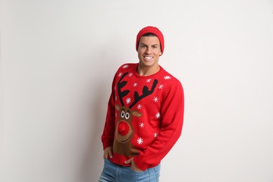 Handsome man in Christmas sweater and hat on white background