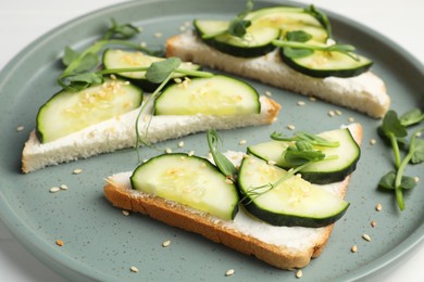 Photo of Tasty cucumber sandwiches with sesame seeds and pea microgreens on colorful plate, closeup