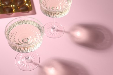Photo of Glasses of expensive white wine on pink background. Space for text
