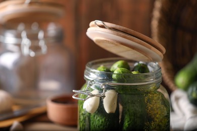 Photo of Glass jar with fresh cucumbers on wooden table, closeup. Canning vegetable