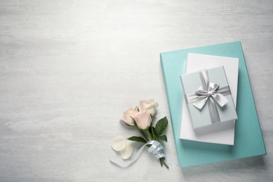 Elegant gift boxes and beautiful flowers on white table, flat lay. Space for text