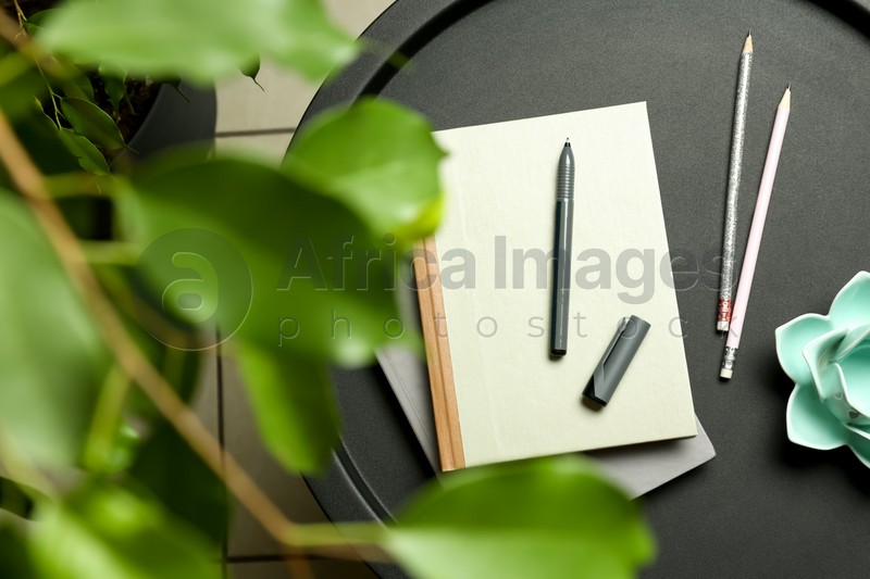 Notebooks, pen, pencils and decor on round table indoors, top view