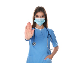 Doctor in protective mask showing stop gesture on white background. Prevent spreading of coronavirus