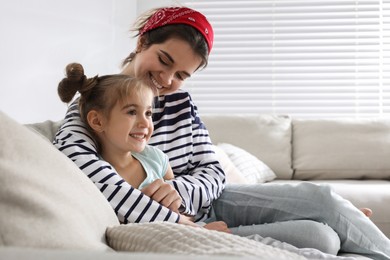 Photo of Young mother and her daughter spending time together on sofa at home