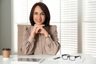 Mature businesswoman sitting at table in office