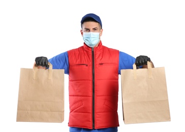 Courier in medical mask holding paper bags with takeaway food on white background. Delivery service during quarantine due to Covid-19 outbreak