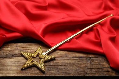 Beautiful golden magic wand and red fabric on wooden table