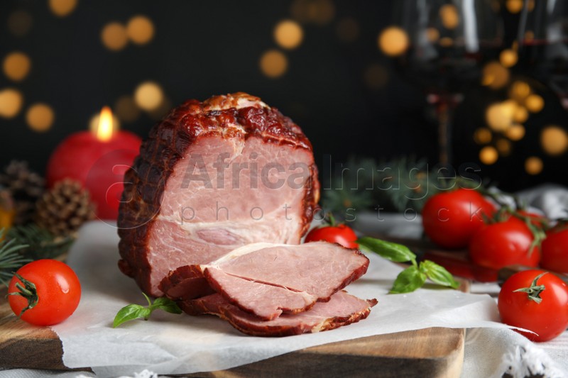 Photo of Delicious ham with tomatoes and basil on table against blurred festive lights, closeup. Christmas dinner