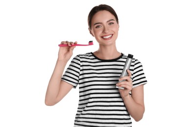 Young woman holding brush and tube with charcoal toothpaste on white background