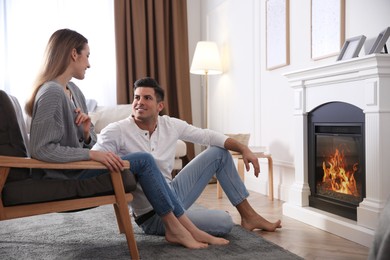 Happy couple resting near fireplace at home