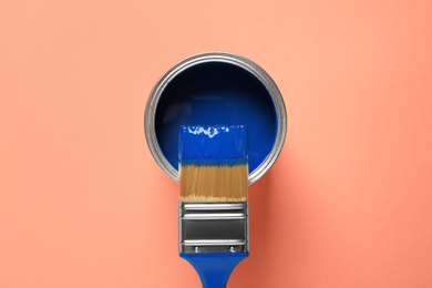 Can of paint and brush on orange background, top view. Color of the year 2020 (Classic blue)