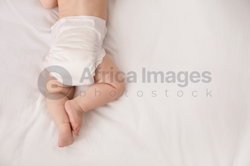Little baby in diaper on bed, top view. Space for text