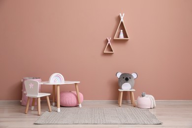 Cute child room interior with furniture, toys and wigwam shaped shelves on pink wall