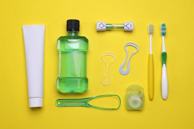 Flat lay composition with tongue cleaners and teeth care products on yellow background