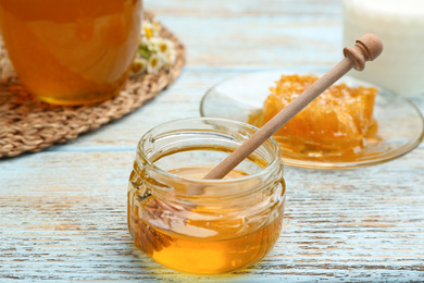 Tasty honey on light blue wooden table, closeup