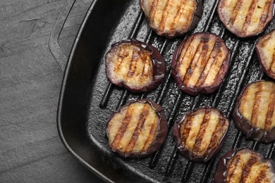 Delicious grilled eggplant slices in pan on black table, top view
