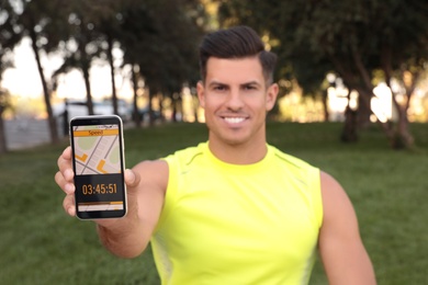 Man showing smartphone with fitness app in park, focus on device