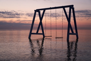 Picturesque view of swing in water on sunrise