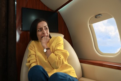 Nervous young woman suffering from aviophobia in airplane