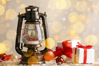 Beautiful snow globe in vintage lantern, gift boxes and Christmas decor on table. Bokeh effect