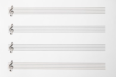 Photo of Sheet with empty staves for music notes and treble clef as background, top view