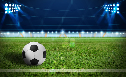 Soccer ball on green football field, space for text 